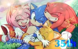 Size: 2048x1293 | Tagged: safe, artist:kot618, amy rose, knuckles the echidna, miles "tails" prower, sonic the hedgehog, 2026, birthday, english text, eyes closed, grass, group, group hug, happy, happy birthday, hugging, looking at viewer, lying down, outdoors, smile, text, wink
